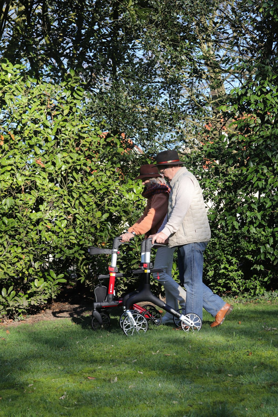 Seniorin mit Rollator und Begleitung im Garten – Symbolbild