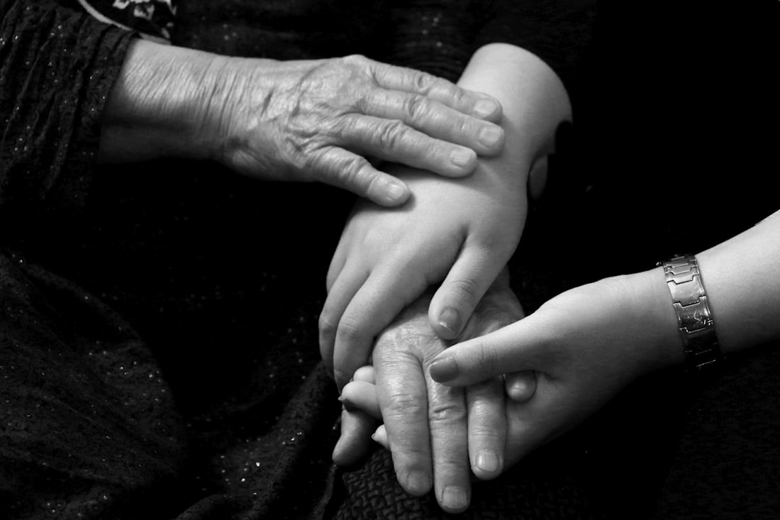 Junge Hände halten die Hände einer Seniorin in Schwarz-Weiß – Symbolbild