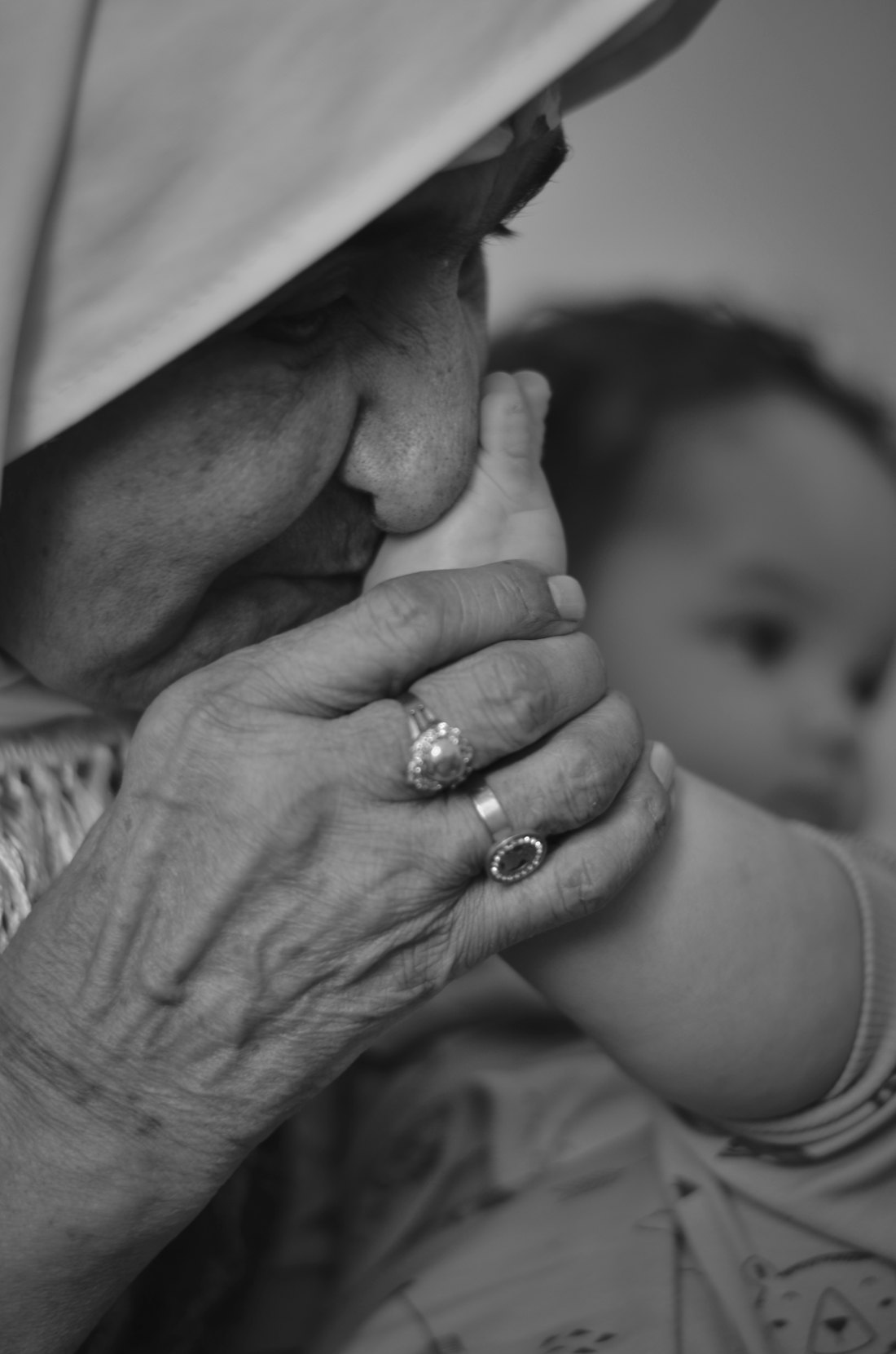 Ältere Frau küsst die Hand eines Babys in Schwarz-Weiß – Symbolbild