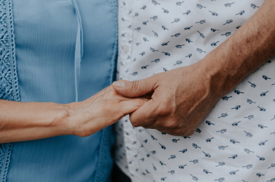 Jüngere Hand hält die Hand einer Seniorin – Symbolbild