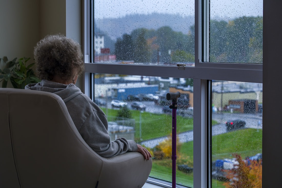 Ältere Frau blickt aus dem Fenster – Symbolbild